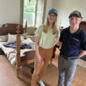 Darley and Kevin standing in front of bed, with a reproduction of Lieutenant Colonel William Fitzhulee's uniform.